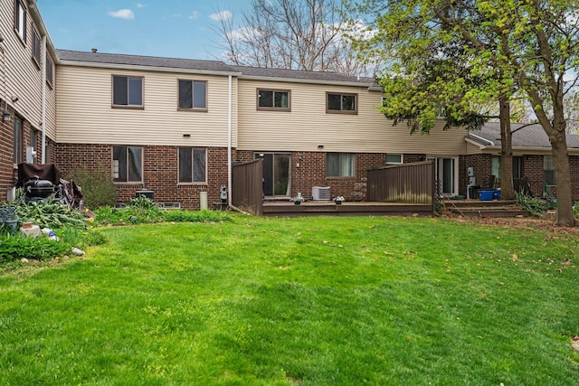 back of house with a deck, a yard, and brick siding