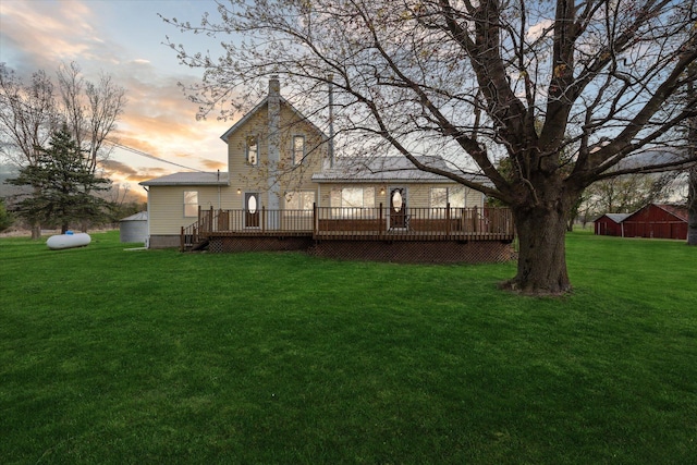 back of property at dusk with a deck and a yard