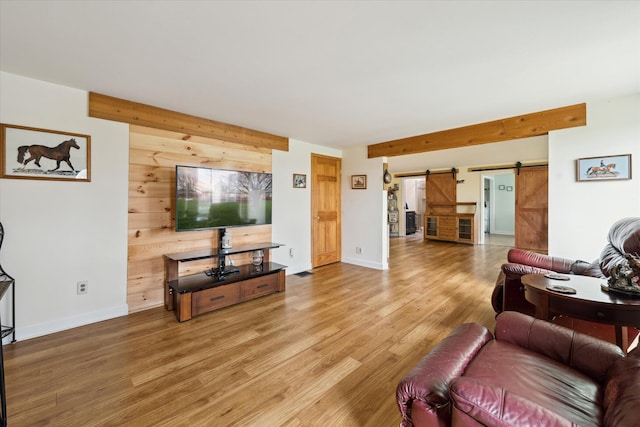 living area with a barn door, light wood-style flooring, and baseboards