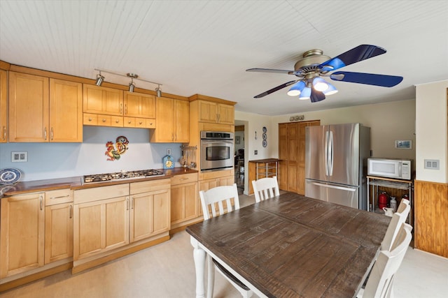 kitchen with dark countertops, stainless steel appliances, ceiling fan, and light brown cabinets