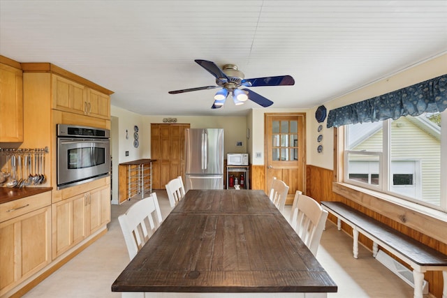 dining room featuring wainscoting, a ceiling fan, and wood walls