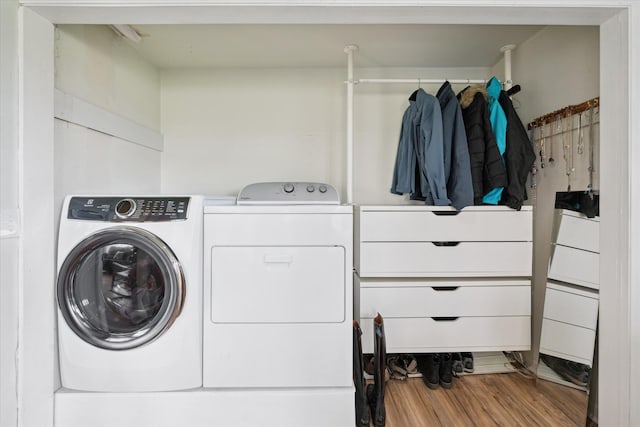 clothes washing area featuring washing machine and dryer, wood finished floors, and laundry area