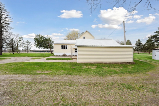 rear view of property with metal roof and a yard