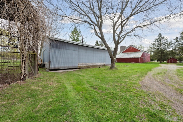 view of yard featuring an outbuilding, dirt driveway, a barn, and fence