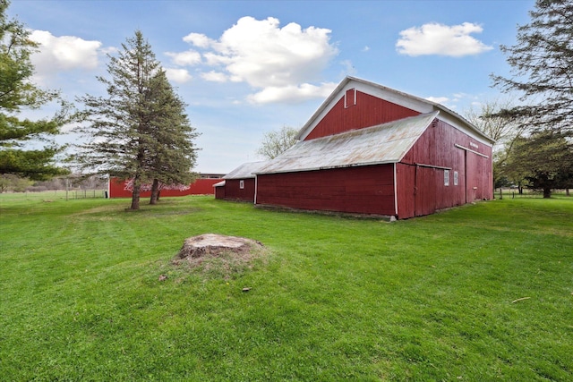 exterior space with a lawn, a barn, and an outbuilding