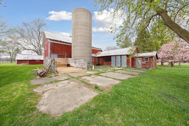 rear view of house with a lawn, a chimney, a barn, and an outbuilding