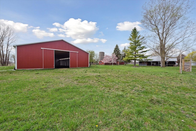 view of yard featuring a pole building, a garage, an outbuilding, and fence