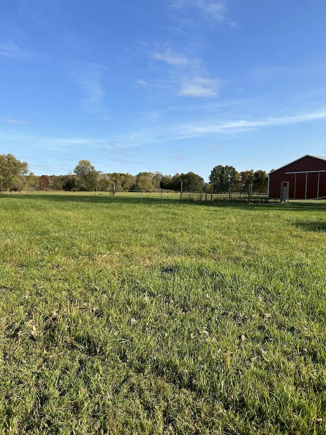 view of yard with a pole building, a rural view, and an outbuilding