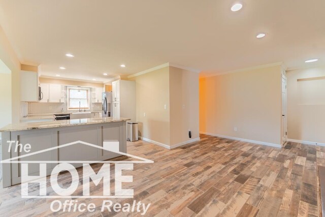 kitchen featuring crown molding, recessed lighting, light wood finished floors, a peninsula, and stainless steel fridge with ice dispenser