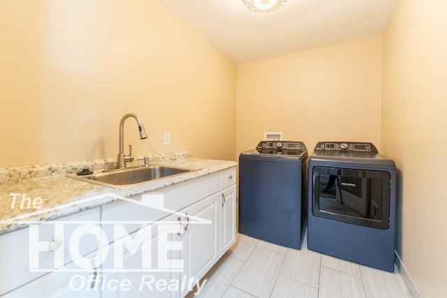 clothes washing area with washing machine and dryer, cabinet space, and a sink