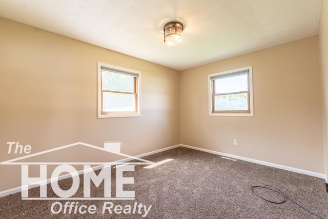 spare room with a healthy amount of sunlight, baseboards, visible vents, and carpet floors