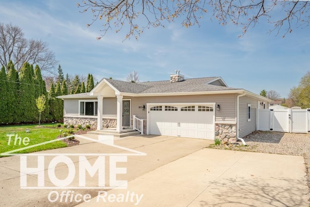 view of front of home with driveway, stone siding, a gate, a front yard, and an attached garage
