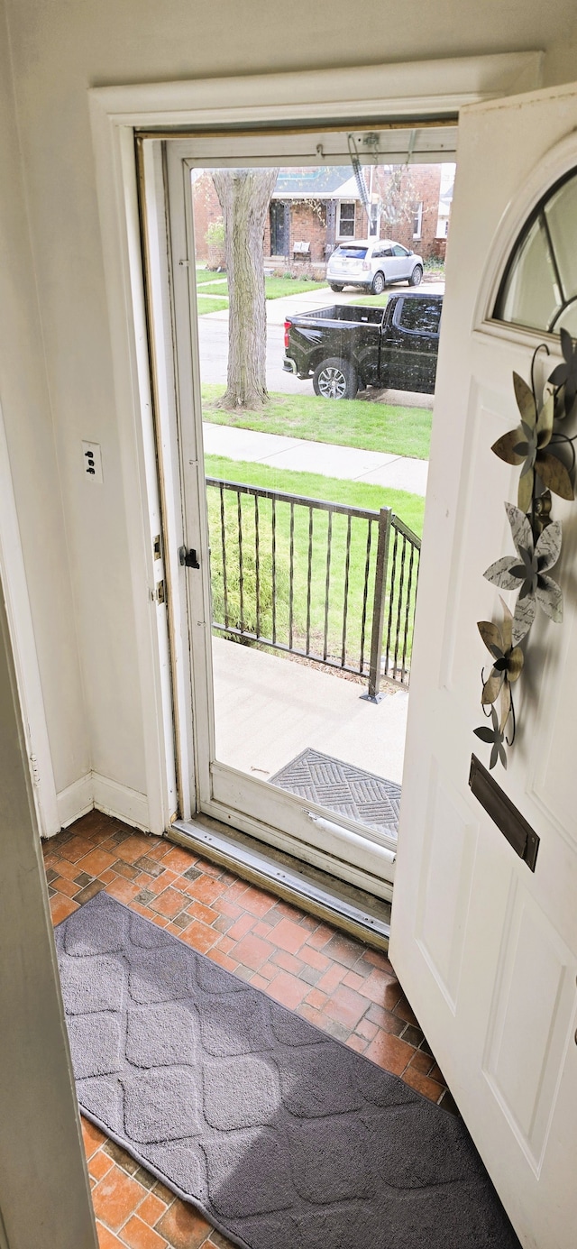 doorway with plenty of natural light, brick floor, and baseboards