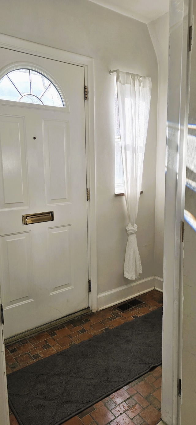entryway featuring brick floor and baseboards