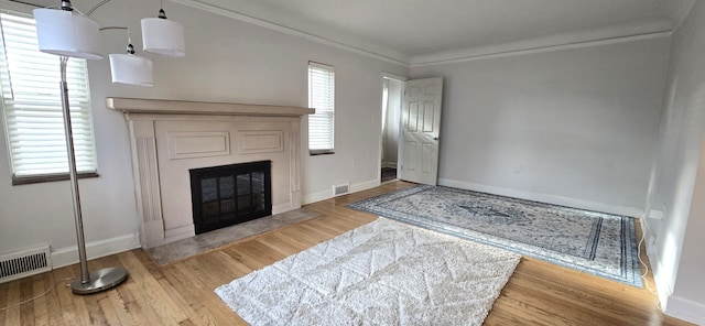 unfurnished living room with baseboards, visible vents, wood finished floors, and a fireplace with flush hearth
