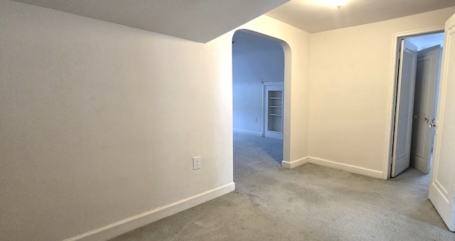 hall with baseboards, arched walkways, and carpet
