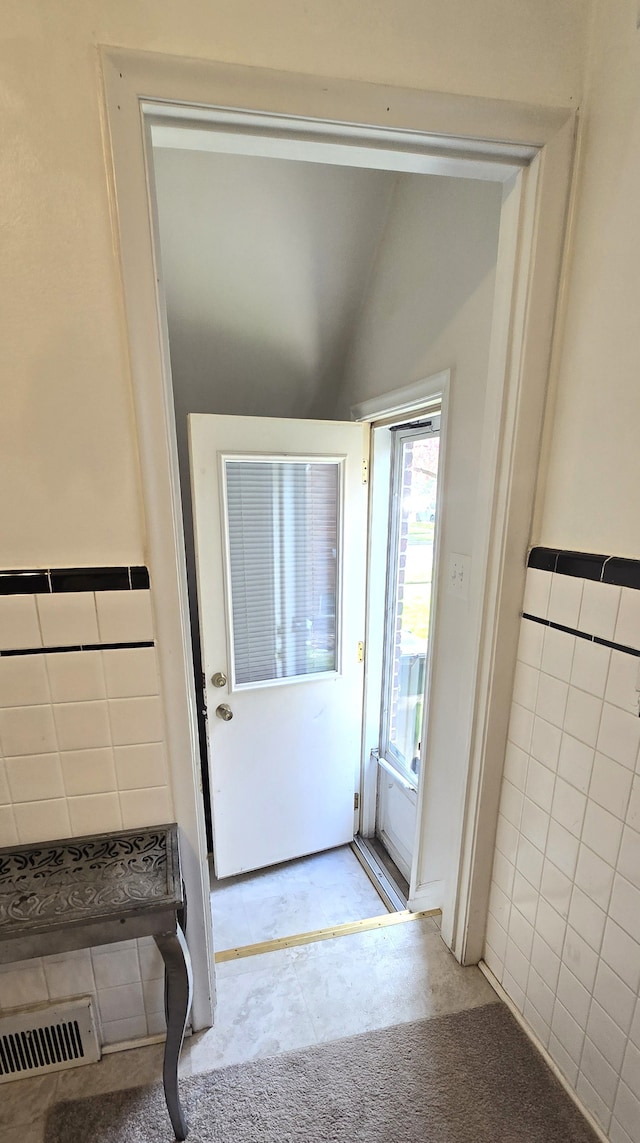 interior space with tile walls, visible vents, and vaulted ceiling