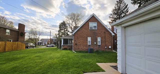view of property exterior featuring a lawn, fence, central AC, and brick siding