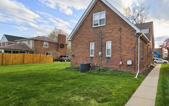 view of home's exterior with brick siding, fence, central air condition unit, and a lawn