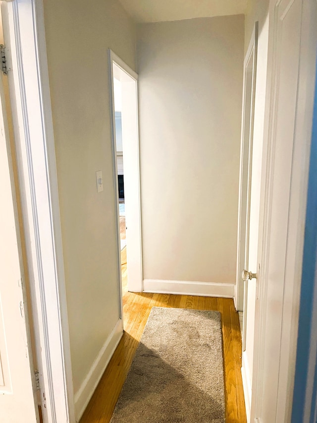 corridor with wood finished floors and baseboards