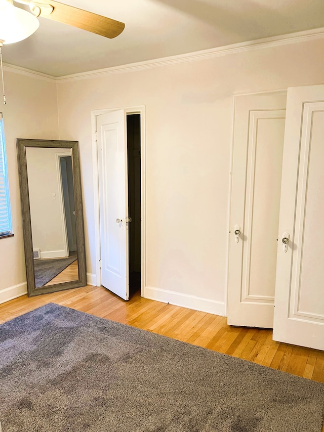 unfurnished bedroom featuring baseboards, ornamental molding, a ceiling fan, and wood finished floors