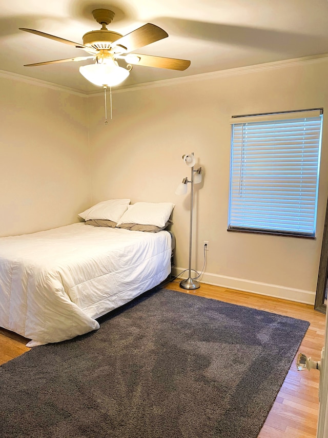bedroom with crown molding, a ceiling fan, light wood-style flooring, and baseboards
