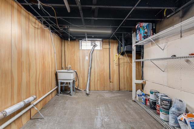 basement featuring wooden walls and a sink