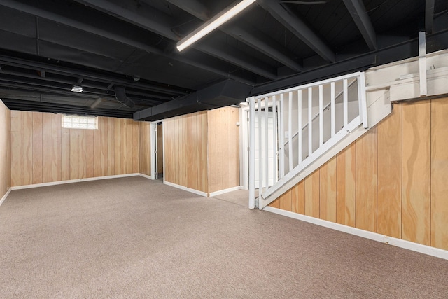 basement with baseboards, wood walls, stairs, and carpet flooring
