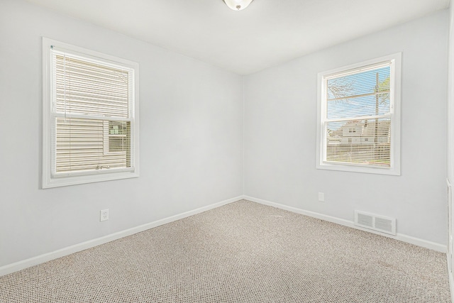 empty room with baseboards, visible vents, and carpet
