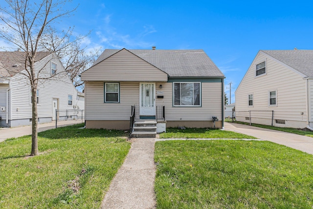 bungalow-style home with fence, a front yard, and roof with shingles