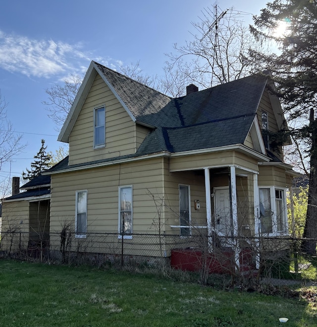 view of home's exterior featuring roof with shingles, fence, a yard, and a chimney