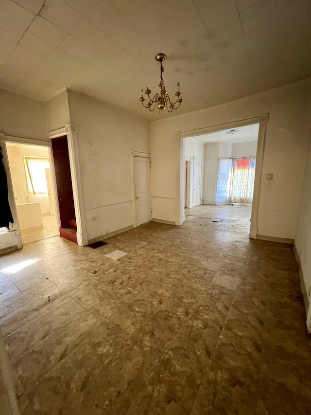 unfurnished dining area featuring baseboards and a notable chandelier