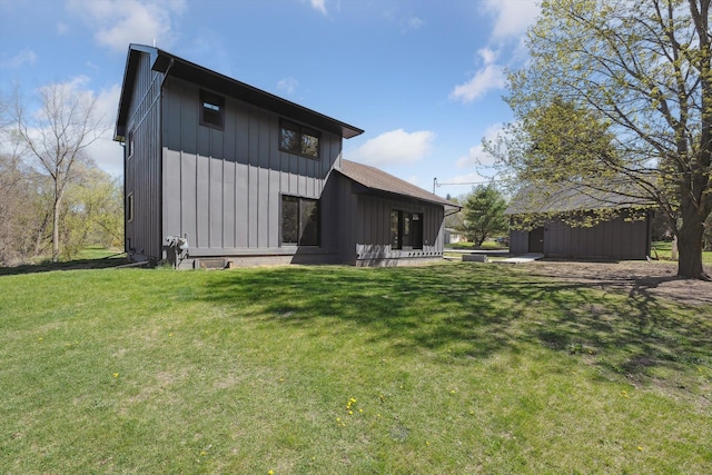rear view of house featuring a lawn and board and batten siding