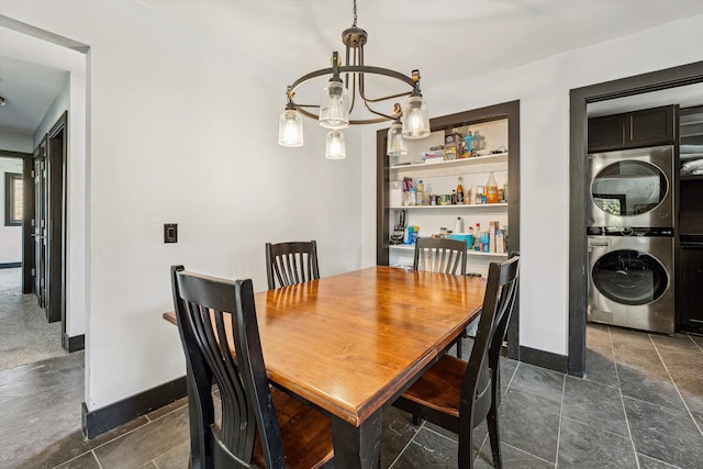 dining room featuring baseboards, stacked washing maching and dryer, and an inviting chandelier