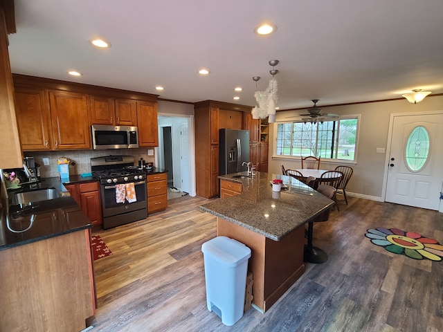24800 Dayton Rd, Armada, MI 48005 - kitchen with a breakfast bar, light wood-style floors, appliances with stainless steel finishes, brown cabinets, and a sink