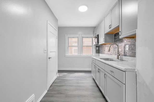 5281 Middlesex St, Dearborn, MI 48126 - kitchen with tasteful backsplash, stainless steel microwave, light wood-style floors, light countertops, and a sink