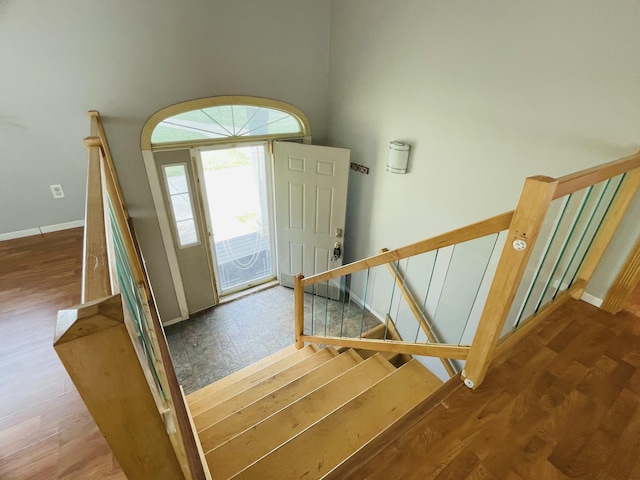 entryway with stairs, baseboards, and wood finished floors