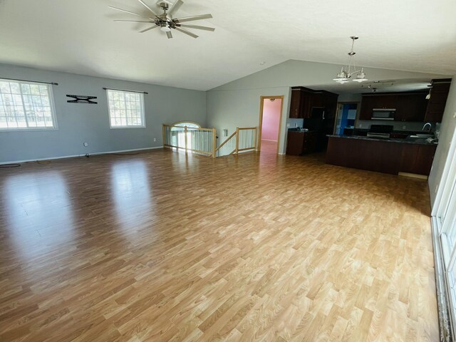 unfurnished living room with a ceiling fan, a sink, light wood finished floors, and vaulted ceiling