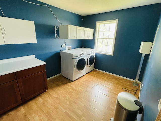 laundry room featuring light wood-type flooring, baseboards, cabinet space, and washing machine and dryer
