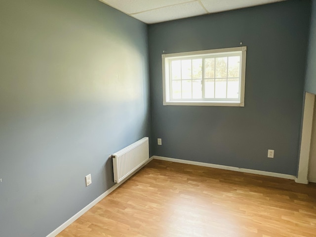 unfurnished room featuring radiator heating unit, baseboards, and light wood-type flooring