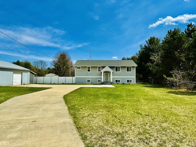 view of front of home with an outdoor structure, fence, a front yard, and concrete driveway