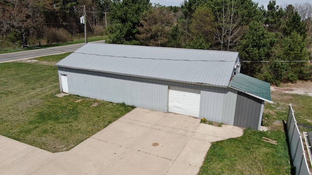 view of outdoor structure featuring concrete driveway, fence, and an outdoor structure