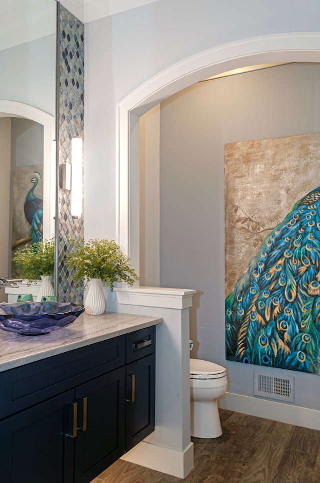 bathroom featuring vanity, baseboards, toilet, and visible vents
