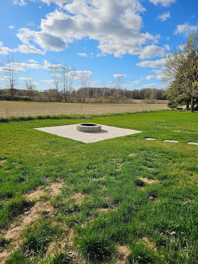 view of yard featuring a rural view, a fire pit, and a patio area