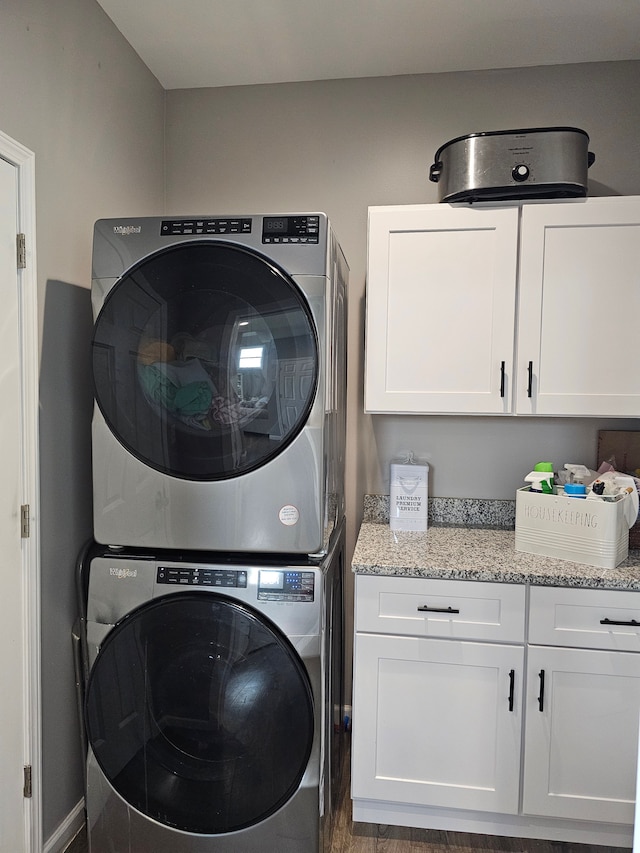 clothes washing area featuring stacked washing maching and dryer and cabinet space