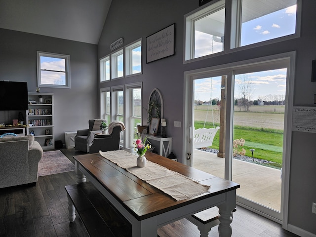 dining room with high vaulted ceiling and wood finished floors