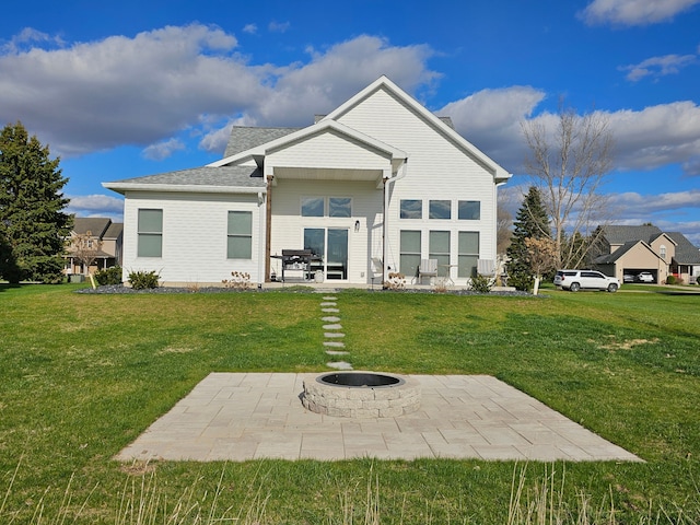 rear view of property with a yard, a fire pit, and a patio area