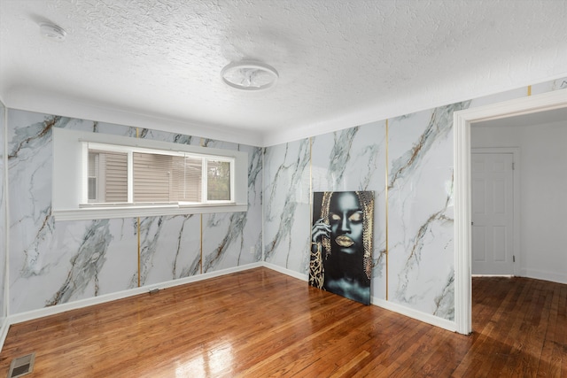 unfurnished living room with baseboards, visible vents, a textured ceiling, and wood-type flooring