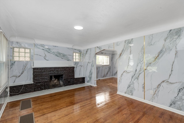 unfurnished living room with a fireplace, wood finished floors, and visible vents