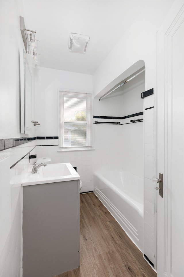 full bathroom featuring tile walls, vanity, shower / bathtub combination, toilet, and wood finished floors